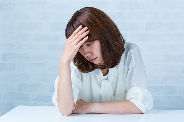 肘をつき額に手をあてる女性